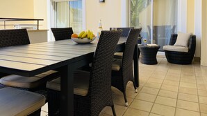 A dining area with a table, chairs, a bowl of fruit, and a bottle of wine. - Beautiful 2 Bed Apartment with Swimming Pool in the Historic Town of Lagos (Lagos)