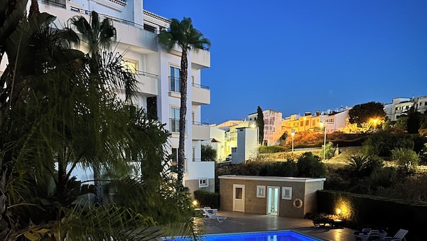 A swimming pool with lounge chairs, a small building, and palm trees. - Beautiful 2 Bed Apartment with Swimming Pool in the Historic Town of Lagos (Lagos)