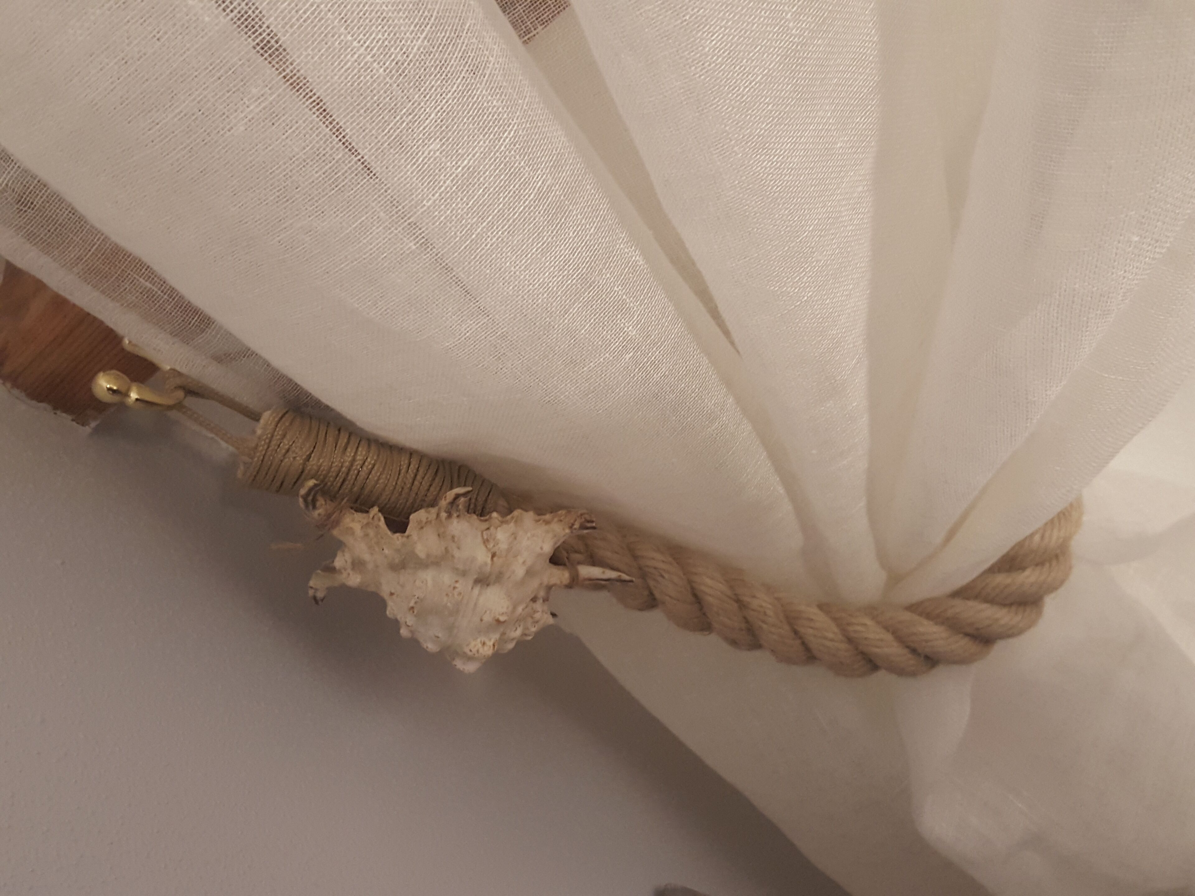 Een gordijn met een touw dat eromheen is vastgebonden, inclusief een decoratieve knoop.
