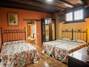Un dormitori amb dos llits, un armari de fusta, una cadira i un quadre a la paret.