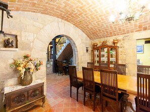 Un espace repas avec un plafond en briques, des murs en pierre, une table à manger en bois et des chaises.