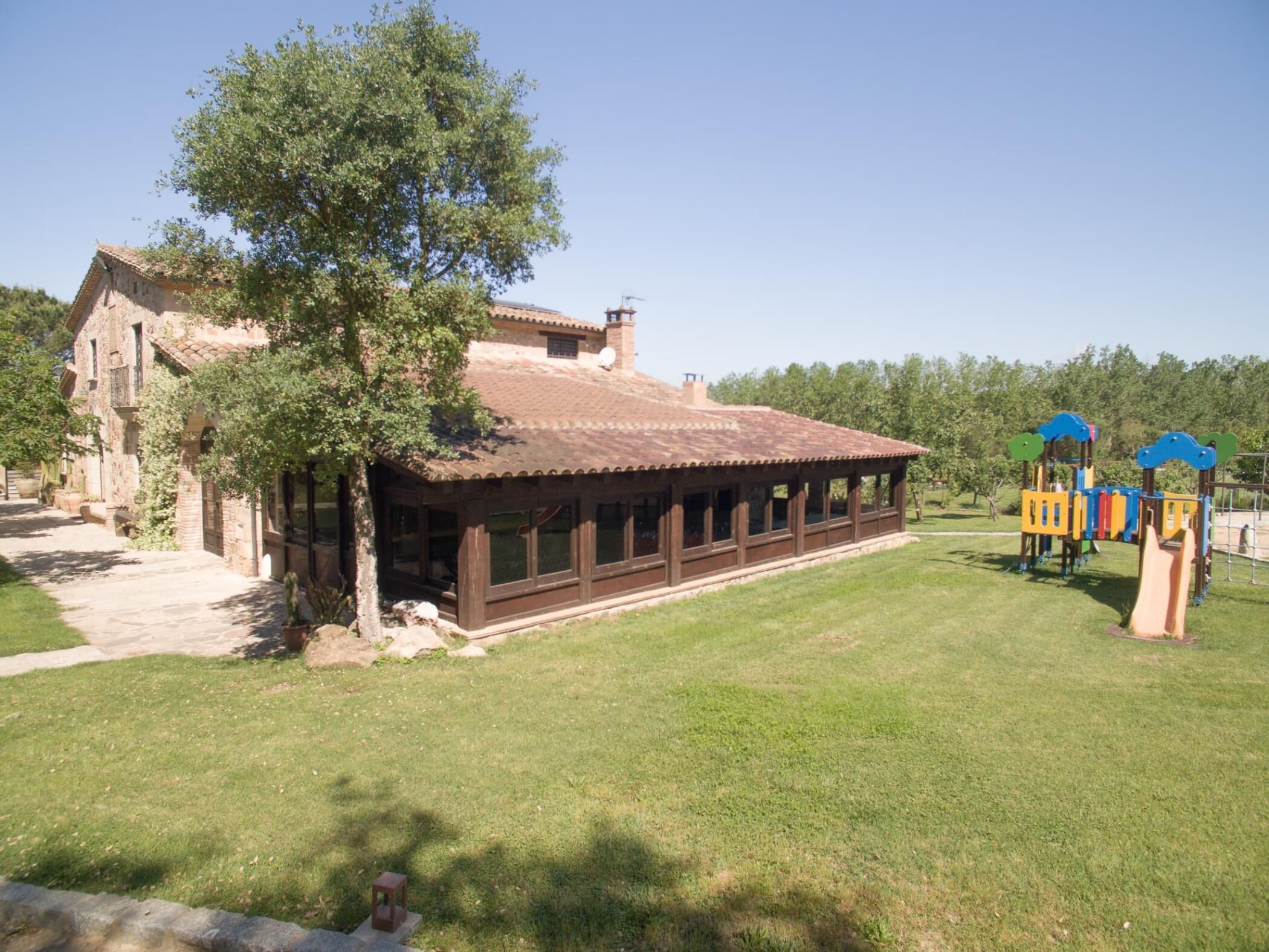 A building with a tiled roof, a covered patio, and a playground with colorful play structures.