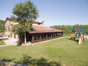 Un edificio con techo de tejas, un porche cubierto y un parque infantil con estructuras de juego coloridas.