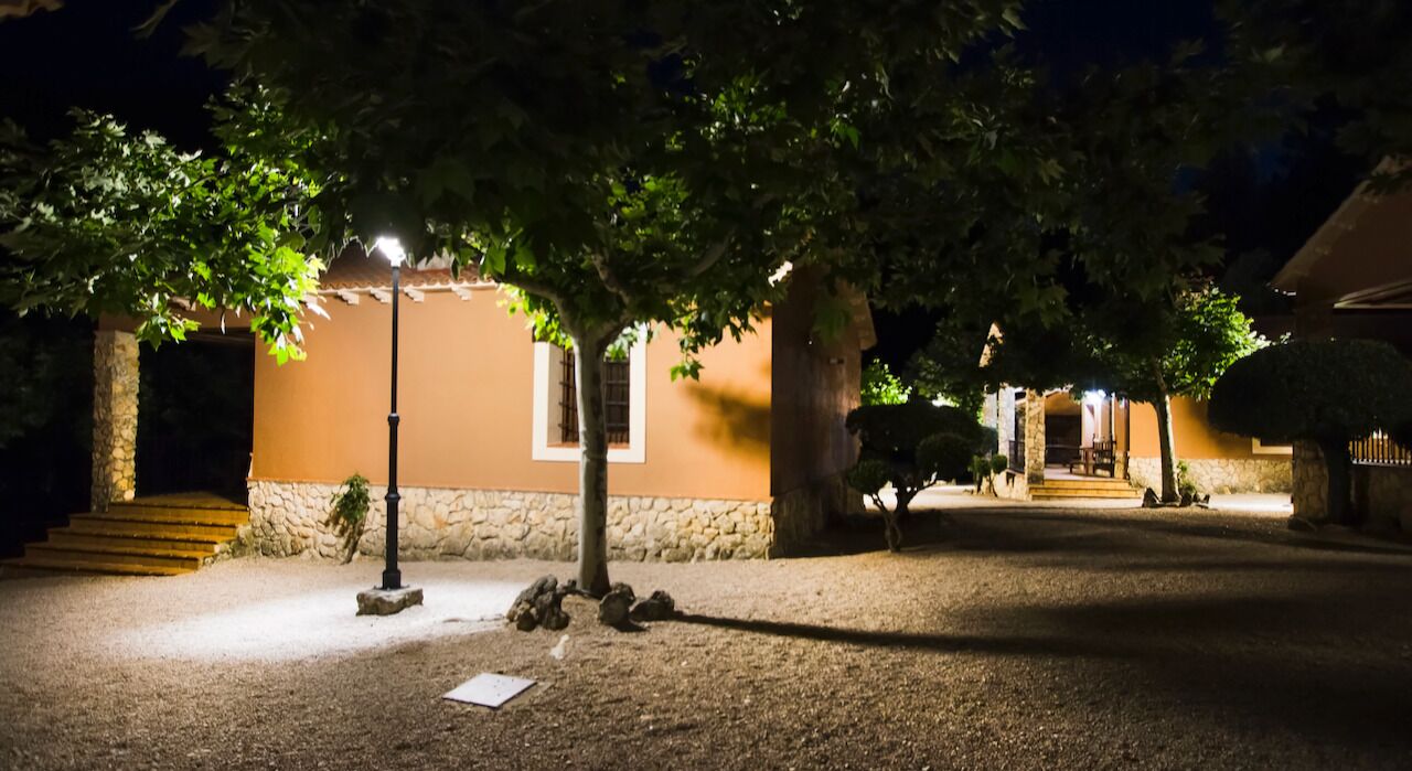 Un edificio con fachada de piedra, una escalera que conduce a la entrada y un camino bien iluminado.