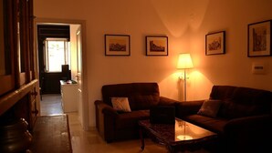 A cozy living room with two brown sofas, a coffee table, and a lamp. There are framed pictures on the wall and a kitchen area in the background. - Rome: Luxury Apartment restructured in the heart of Rome (Roma)