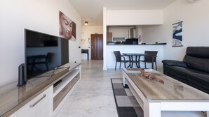 A modern living room with a flat-screen TV, a wooden coffee table, a black leather sofa, and a dining area with a table and chairs. - Oceanside modern apartment [80] (Lagos)
