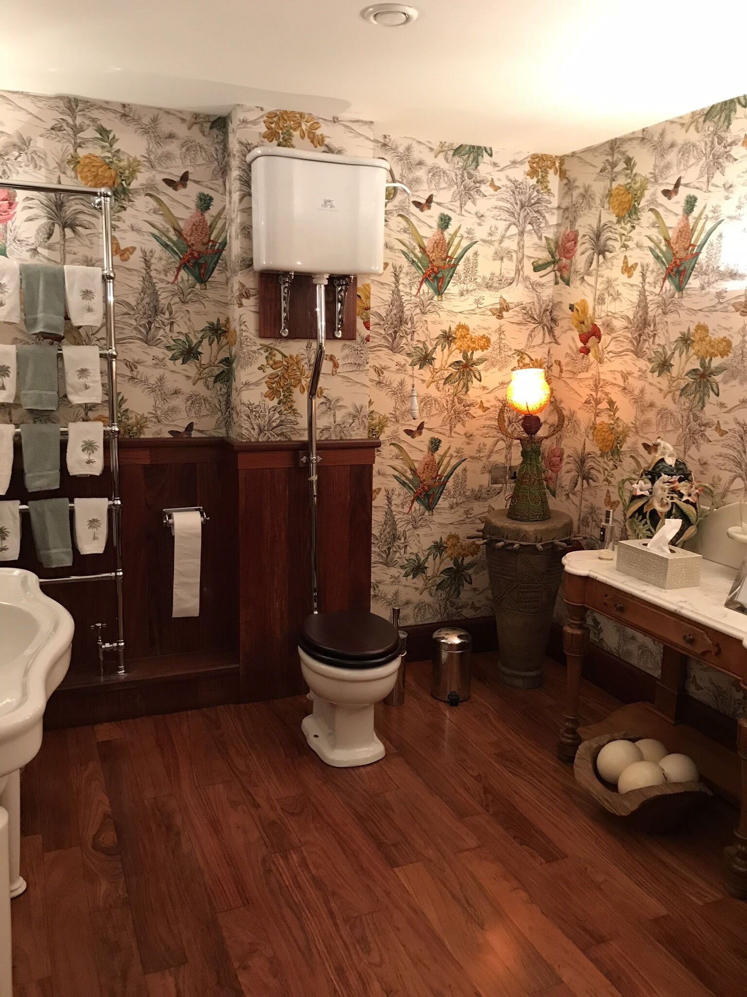 Une salle de bain équipée d’un WC, d’un lavabo, d’un porte-serviettes et d’une plante décorative.