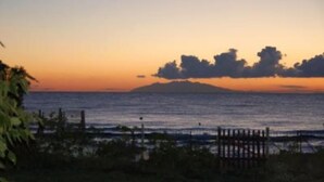Ein Küsten-Sonnenuntergang mit einem Holzzaun im Vordergrund.