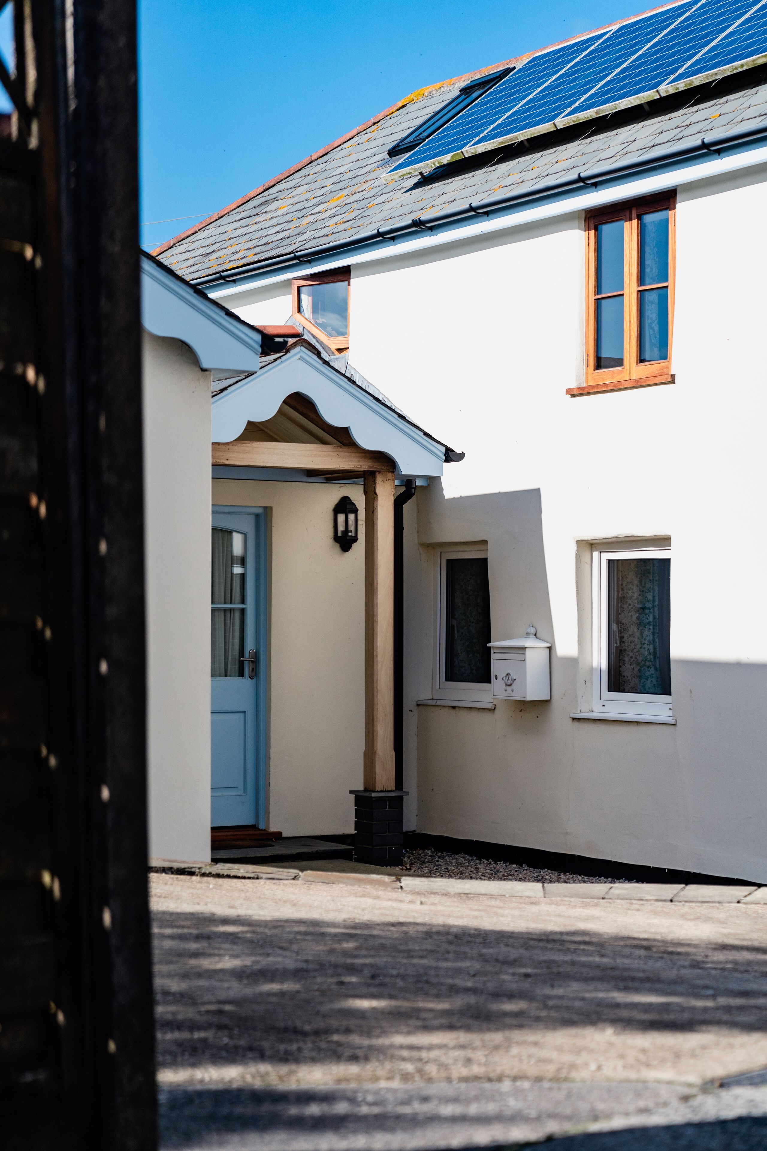 A house with a blue door, a small porch, and a solar panel on the roof.