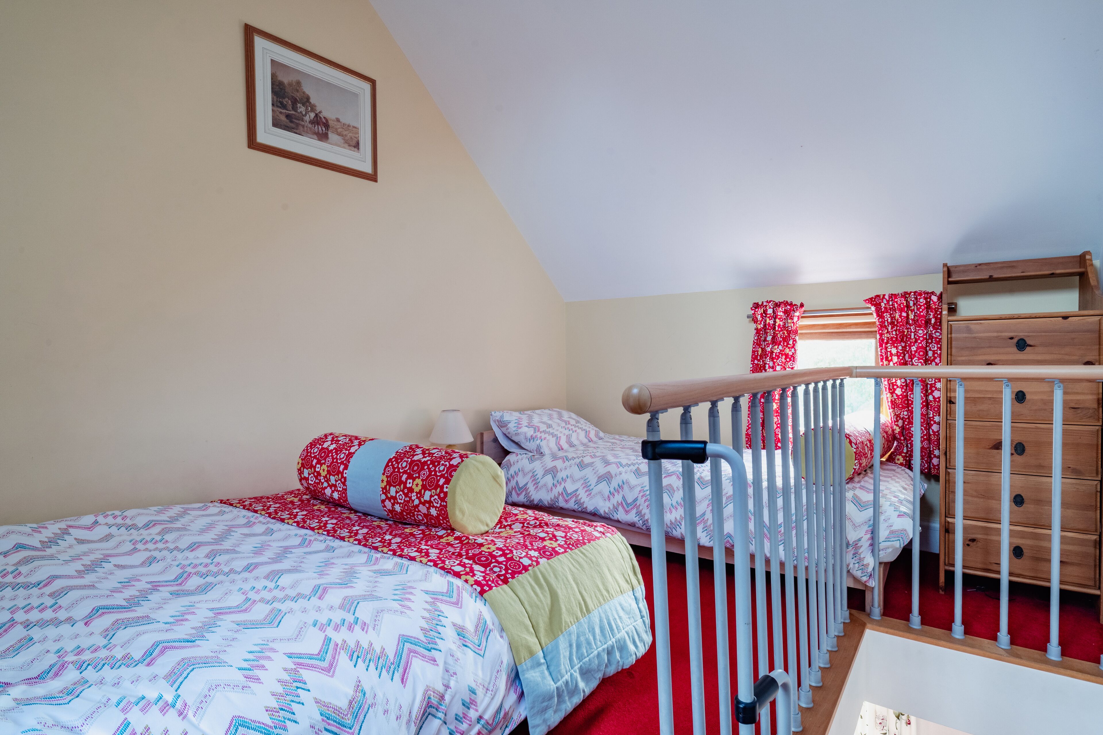 Ein Schlafzimmer mit zwei Betten, einer Holzkommode und einem Fenster mit roten Vorhängen.