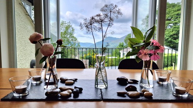 Une table ornée de vases de fleurs et de bougies, placée devant un paysage extérieur pittoresque.