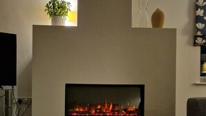 Un salon avec une cheminée, une table en bois et un magazine.