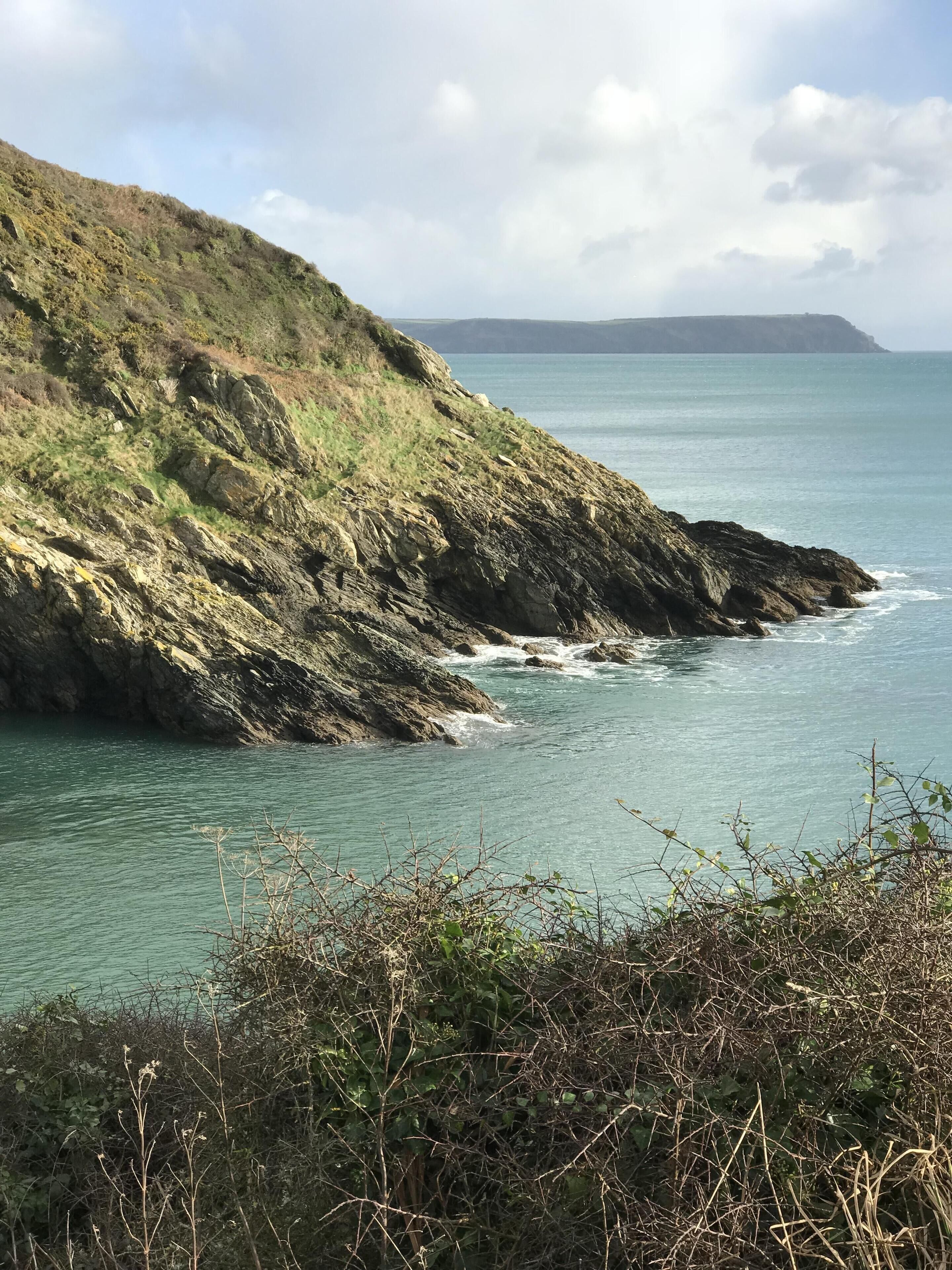 A coastal landscape with rocky cliffs and a view of the sea.