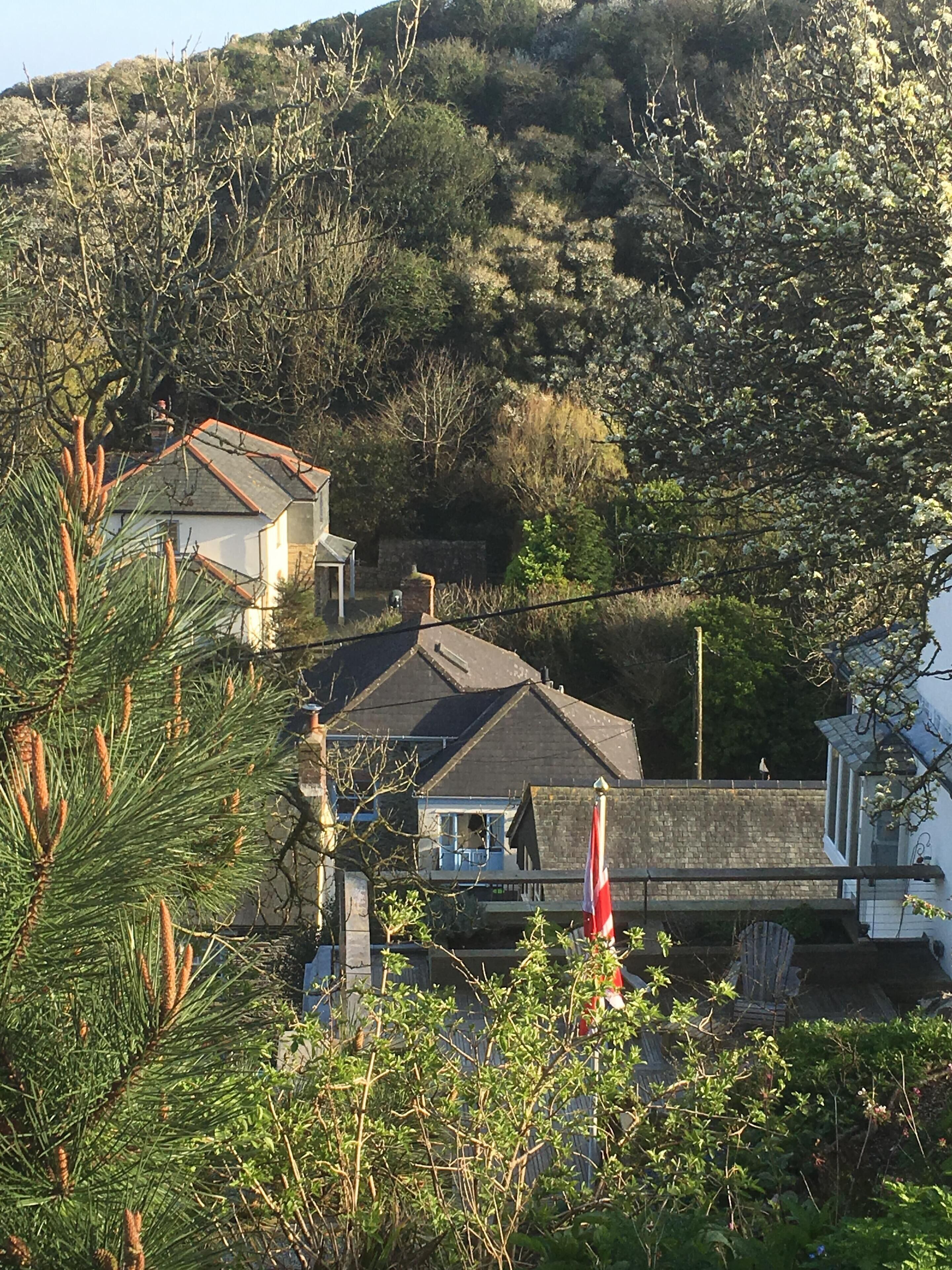 A coastal village with traditional houses, a stone wall, and a flag.