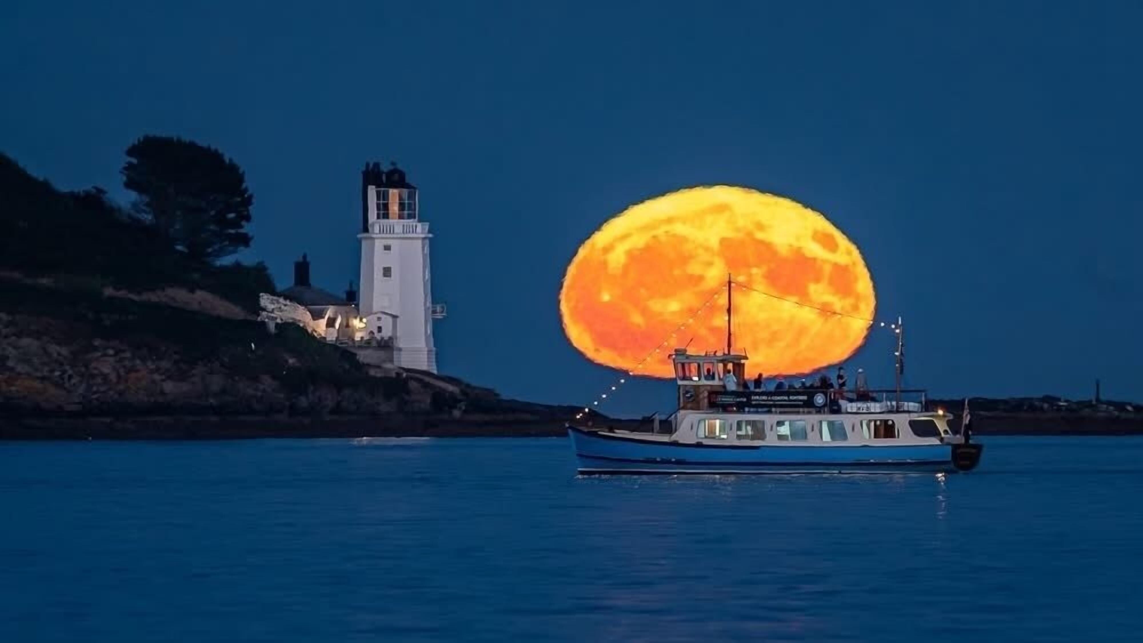 A boat on calm water with a large moon in the sky.