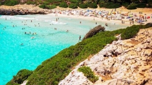 Une plage côtière bordée d’une eau turquoise et limpide, de falaises rocheuses et d’une végétation luxuriante.