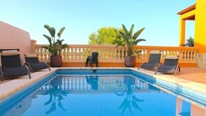 Une piscine avec des chaises longues et des plantes en pot.