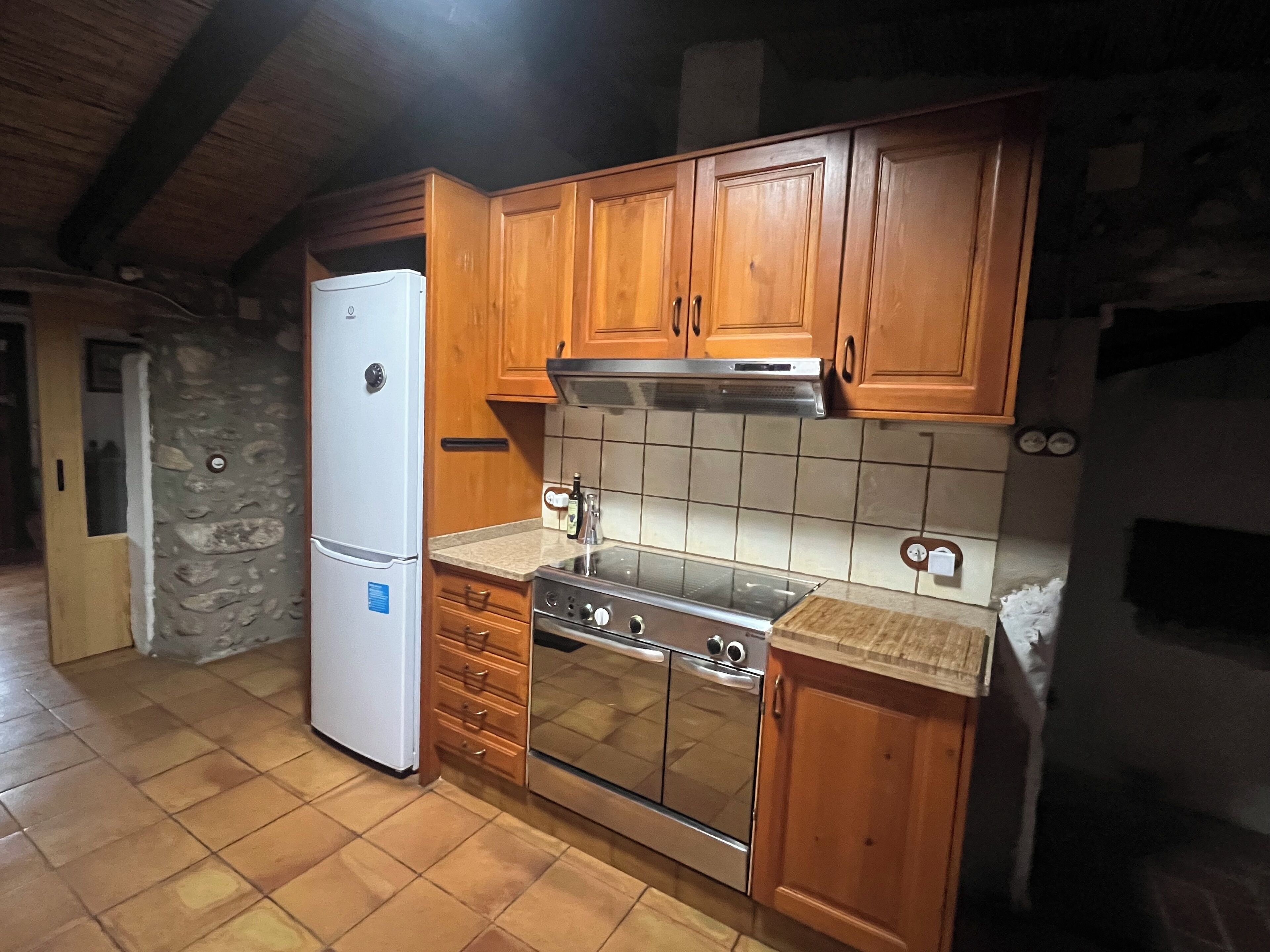 A kitchen with wooden cabinets, a white refrigerator, a stove, and a tiled backsplash.