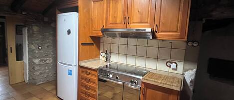 A kitchen with wooden cabinets, a white refrigerator, a stove, and a tiled backsplash.