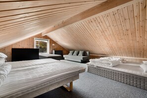 Un dormitorio acogedor en el ático con dos camas, un sofá y un escritorio.