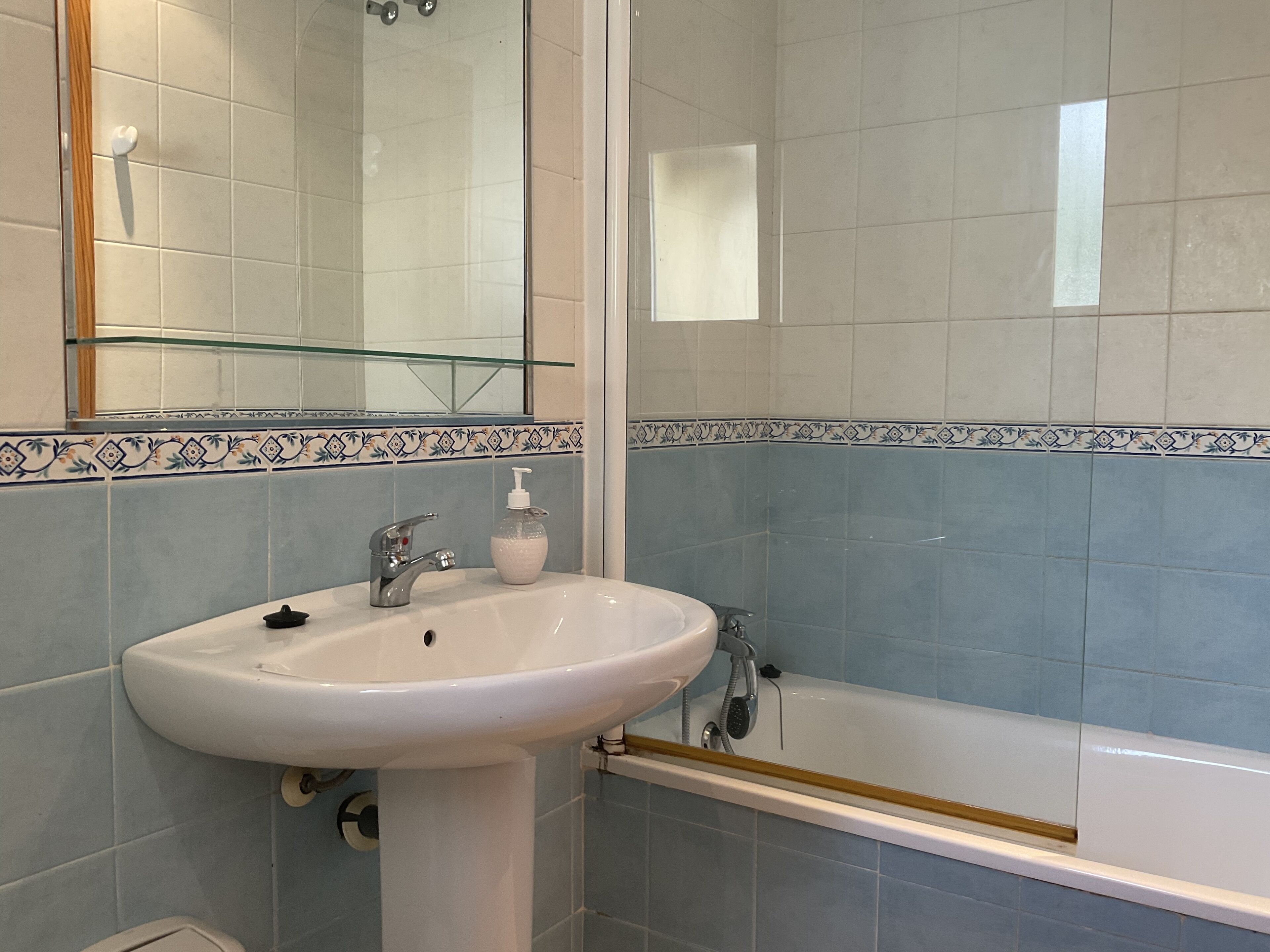 A bathroom with a white sink, a mirror, and a bathtub.