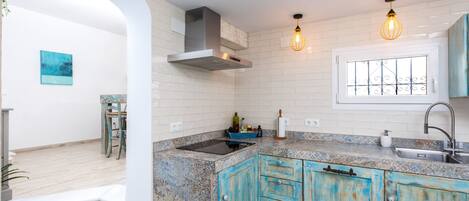 A kitchen with white subway tiles, a stainless steel range hood, a double sink, and blue cabinets.