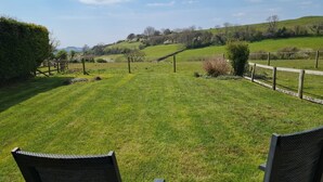 A grassy outdoor area with a wooden fence, a bench, and a view of rolling hills. - Buckingham Cottage : Idyllic Getaway Cottage in the rolling hills of Dorset (West Milton)