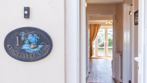 Ein Flur mit einer Tür zu einem Zimmer. An der Wand befindet sich eine Schild mit der Aufschrift 'Kingfisher Lodge'.