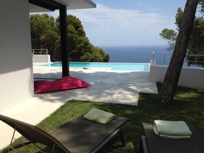 A modern outdoor area with a pool, lounge chairs, and a view of the sea. - Contemporary house with a splendid sea view and fiber (Begur)