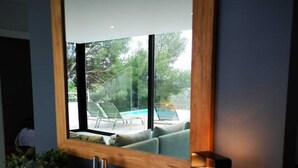 Un baño moderno con un espejo grande, tocador de madera y vistas a una piscina exterior.