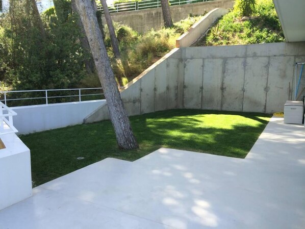 A modern outdoor area with a concrete wall, a grassy patch, and a white bench. - Contemporary house with a splendid sea view and fiber (Begur)