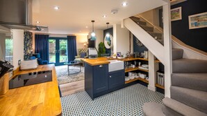 A modern kitchen with a central island, built-in cabinets, and a staircase leading to an upper level. - No. 33 Cottage 2, Thornham, Norfolk (Thornham)