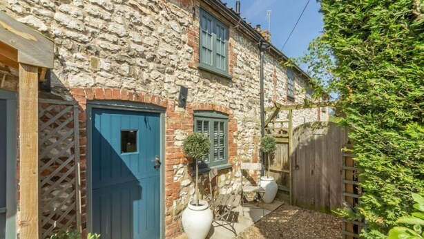 A stone building with a blue door, a wooden fence, and a small garden area with potted plants. - No. 33 Cottage 2, Thornham, Norfolk (Thornham)