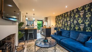 A modern living room with a blue sofa, a round coffee table, and a fireplace. - No. 33 Cottage 2, Thornham, Norfolk (Thornham)