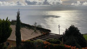 Une vue sur la côte, avec un ciel dégagé, une mer calme et un bâtiment doté d’un toit en tuiles et d’un escalier menant à l’eau.