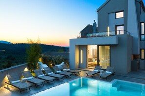A modern house with a swimming pool, lounge chairs, and a view of the countryside. - Villa Blanche - White Mountain Gaze by etouri (Chania)