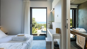 A modern hotel room with a large window, a bed, a desk, and a view of the outdoors. - Villa Blanche - Top quality villa surrounded by nature, close to the beach (Chania)