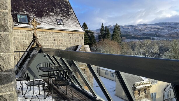 Ein mit Schnee bedeckter Deck mit Außenmöbeln und Blick auf eine Berglandschaft.