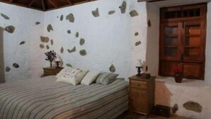 A bedroom with a bed, a nightstand, and a wooden wardrobe. - Rural house (full rental) Finca Los Ciruelos for 2 people (Icod de los Vinos)