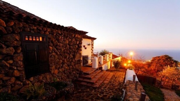 A stone building with a staircase leading to a white door, surrounded by a stone pathway and vegetation. - Rural house (full rental) Finca Los Ciruelos for 2 people (Icod de los Vinos)