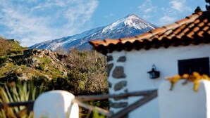 A mountain with a snow-capped peak in the background, a stone building with a tiled roof in the foreground, and a clear blue sky. - Rural house (full rental) Finca Los Ciruelos for 2 people (Icod de los Vinos)