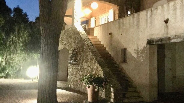Ein Gebäude mit einer Steintreppe, die zu einem zweiten Stock führt, umgeben von Bäumen.