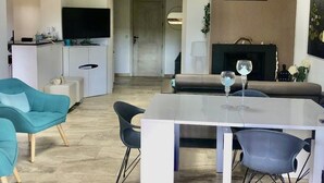 Ein modernes Wohnzimmer mit Essbereich, einer Couch und einem Fernseher.