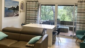 Ein modernes Wohnzimmer mit einer Couch, einem Esstisch und Blick ins Freie.