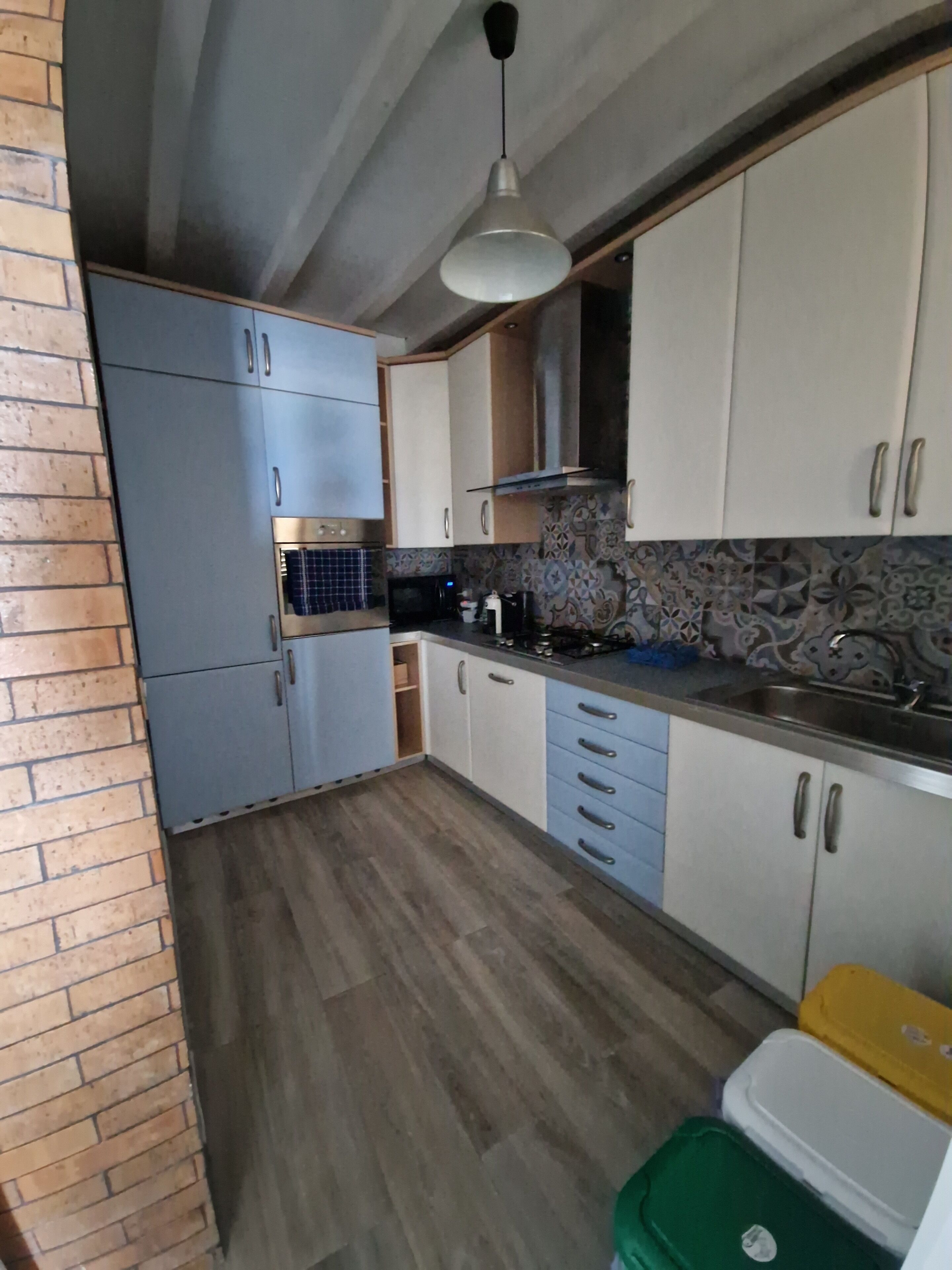 A kitchen with cabinets, a microwave, a sink, and a hanging light fixture.