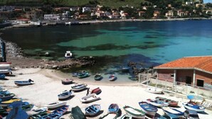 A coastal town with boats on a sandy beach and buildings in the background.