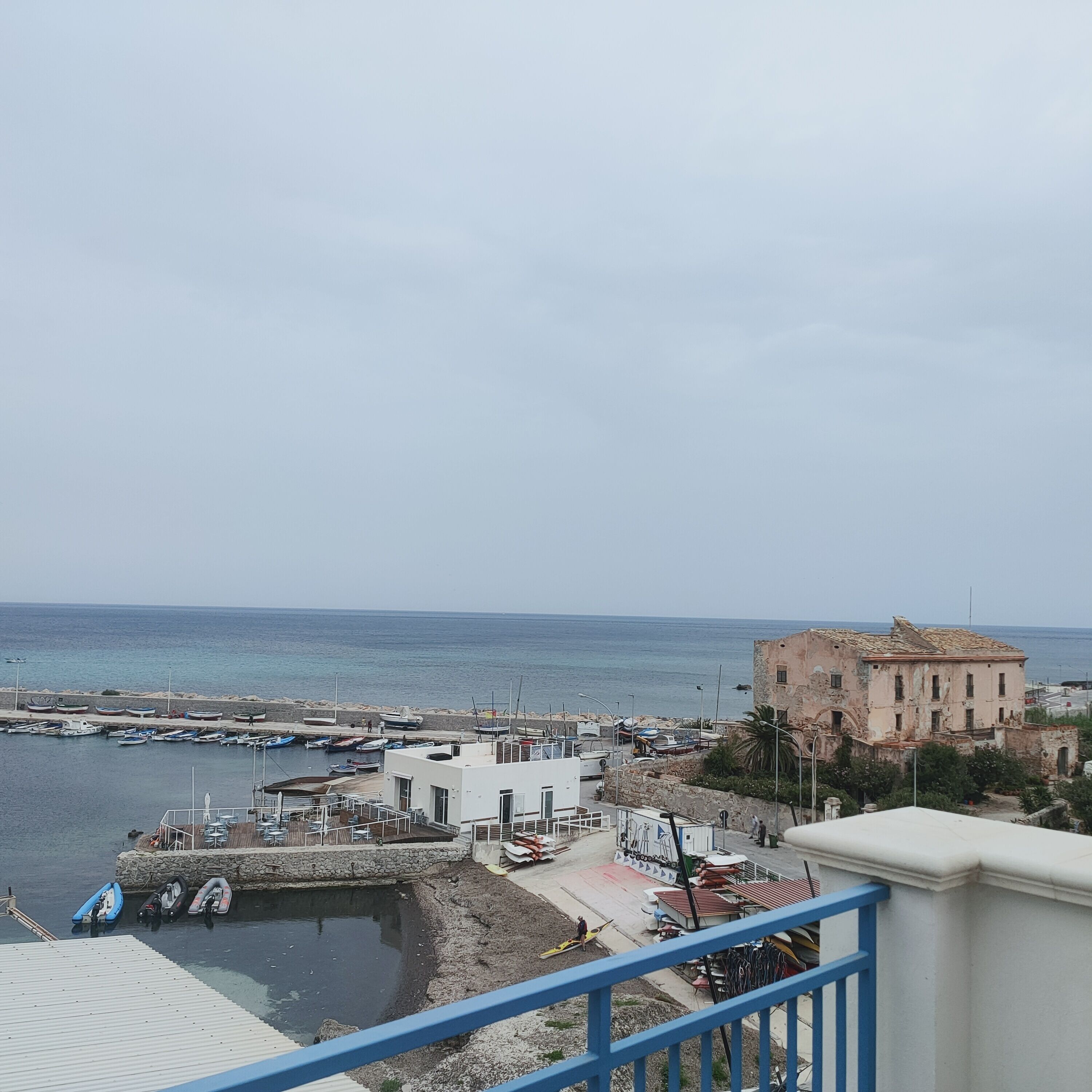 A coastal view with a marina, boats, and a historic building.