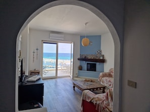 A living room with a view of the beach, a fireplace, and a dining area. - Gorgeous Attic Room by the Sea. Breathtaking view (Palermo)