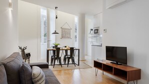 A modern living room with a sofa, TV, dining table, chairs, and a kitchen area. - Galerias On Trend Nightlife by Feel Porto (Oporto)