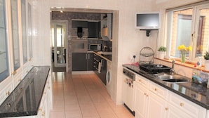 A modern kitchen with white cabinetry, a black countertop, a built-in oven, microwave, and dishwasher. There is a window with a view of the outside. - Abbot`s House in Doonfoot (Doonfoot)